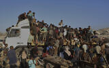 Palestinians get food and humanitarian aid from the back of a truck as it moves along the Morag corridor near Rafah, in the southern Gaza Strip, Monday, Aug. 4, 2025. (AP/Mariam Dagga)
