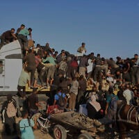 Palestinians get food and humanitarian aid from the back of a truck as it moves along the Morag corridor near Rafah, in the southern Gaza Strip, Monday, Aug. 4, 2025. (AP/Mariam Dagga)