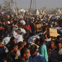 Palestinians carry packages of food taken from a humanitarian aid convoy that moved along the Morag corridor near Rafah, in the southern Gaza Strip, August 4, 2025. (AP Photo/Mariam Dagga)