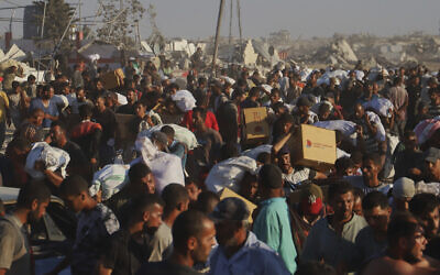 Palestinians carry packages of food taken from a humanitarian aid convoy that moved along the Morag corridor near Rafah, in the southern Gaza Strip, August 4, 2025. (AP Photo/Mariam Dagga)