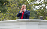 US President Donald Trump shouts to reporters as he surveys the grounds from the roof above the Colonnade that goes to the West Wing of the White House, August 5, 2025, in Washington. (AP Photo/Alex Brandon)