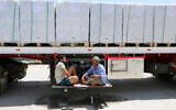 Truck drivers, who carry humanitarian aid, drink tea as they wait to enter Rafah crossing between Egypt and the Gaza Strip, August 6, 2025. (Khaled Elfiqi/AP)