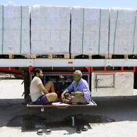 Truck drivers, who carry humanitarian aid, drink tea as they wait to enter Rafah crossing between Egypt and the Gaza Strip, August 6, 2025. (Khaled Elfiqi/AP)