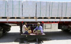 Truck drivers, who carry humanitarian aid, drink tea as they wait to enter Rafah crossing between Egypt and the Gaza Strip, August 6, 2025. (Khaled Elfiqi/AP)
