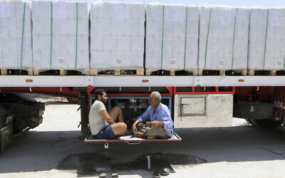 Truck drivers, who carry humanitarian aid, drink tea as they wait to enter Rafah crossing between Egypt and the Gaza Strip, August 6, 2025. (Khaled Elfiqi/AP)