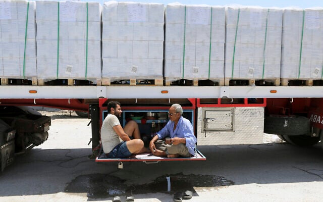 Truck drivers, who carry humanitarian aid, drink tea as they wait to enter Rafah crossing between Egypt and the Gaza Strip, August 6, 2025. (Khaled Elfiqi/AP)