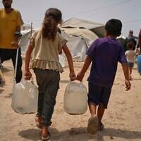 In the summer heat, Palestinian children carry jerrycans after collecting water from a distribution point in Gaza City, August 12, 2025. (AP Photo/Jehad Alshrafi)