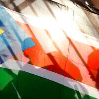 FILE - The silhouettes of South Sudanese people are seen through a South Sudanese flag as they line up to cast their votes in Juba, South Sudan, on January 9, 2011. (AP Photo/Jerome Delay, File)