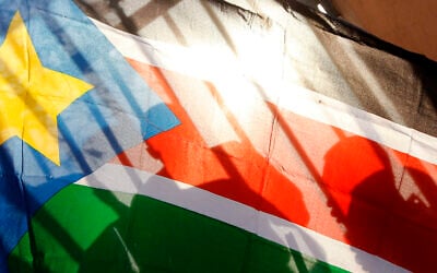 FILE - The silhouettes of South Sudanese people are seen through a South Sudanese flag as they line up to cast their votes in Juba, South Sudan, on January 9, 2011. (AP Photo/Jerome Delay, File)
