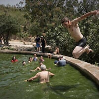 A man jumps in the water as people cool off in the Ein Lavan spring, amid a heat wave, in the outskirts of Jerusalem, August 13, 2025. (AP/Mahmoud Illean)