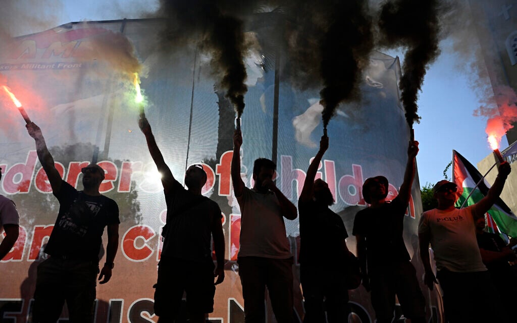 Protesters hold flares during a rally to protest the arrival of a cruise ship with Israelis at the Piraeus port in Greece on August 14, 2025. (AP/Michael Varaklas)