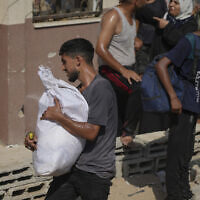 A Palestinian collects humanitarian aid after it was airdropped into Gaza City, northern Gaza Strip, August 14, 2025. (AP Photo/Jehad Alshrafi)