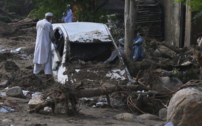 Local residents look at a car trapped in the mud after flash flooding on the outskirts of Pir Baba, Buner district, in Pakistan's northwest, August 16, 2025. (AP/Muhammad Sajjad)