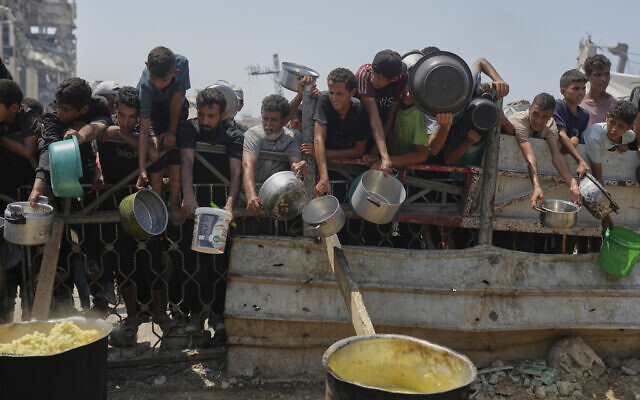 Palestinians struggle to get donated food at a community kitchen in Gaza City, northern Gaza Strip, August 16, 2025. (AP Photo/Jehad Alshrafi)