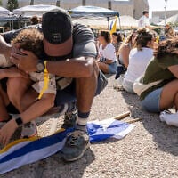 People sit on the ground and cover their heads as a sirens warn of an incoming missile fired from Yemen during a protest demanding the immediate release of hostages held by Hamas, in Tel Aviv, August. 17, 2025. (AP Photo/Maya Levin)