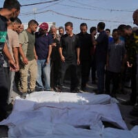 Palestinians stand next to bodies of their relatives, who were killed in an Israeli airstrike, outside the Al-Aqsa Hospital in Deir al-Balah, August 19, 2025. (AP Photo/Abdel Kareem Hana)