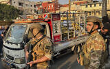 Army soldiers stand next to a pickup carrying weapons handed over by Palestinian factions at the Burj al-Barajneh Palestinian refugee camp in Beirut, Lebanon on August 21, 2025. (AP/Hussein Malla)