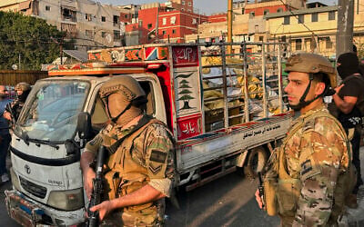 Army soldiers stand next to a pickup carrying weapons handed over by Palestinian factions at the Burj al-Barajneh Palestinian refugee camp in Beirut, Lebanon on August 21, 2025. (AP/Hussein Malla)