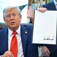 US President Donald Trump holds up a signed executive order requiring the Justice Department to investigate instances of flag burning, in the Oval Office of the White House, Monday, Aug. 25, 2025, in Washington. (AP Photo/Evan Vucci)