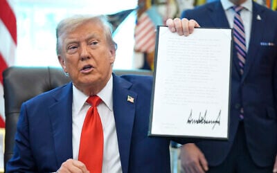 Illustrative: US President Donald Trump holds up a signed executive order requiring the Justice Department to investigate instances of flag burning, in the Oval Office of the White House, August 25, 2025. (AP Photo/Evan Vucci) Illustrative: US President Donald Trump holds up a signed executive order requiring the Justice Department to investigate instances of flag burning, in the Oval Office of the White House, August 25, 2025. (AP Photo/Evan Vucci)