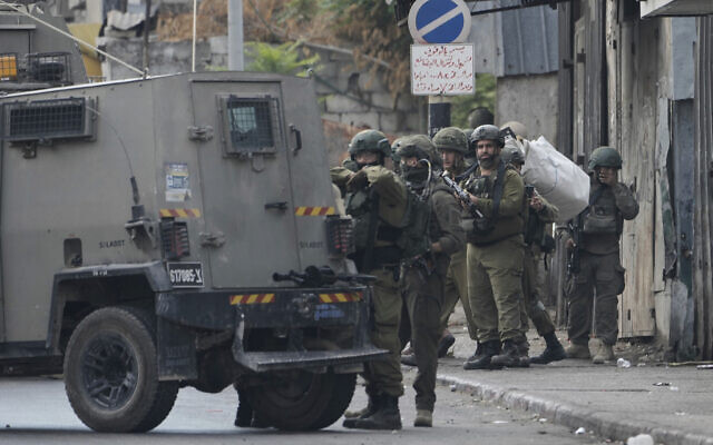 Members of Israeli security forces stand next to an armored vehicle during a military raid in the West Bank city of Nablus, Wednesday, August 27, 2025. (AP/Majdi Mohammed)