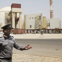 In this Aug. 21, 2010 file photo, an Iranian security officer directs media at the Bushehr nuclear power plant, with the reactor building seen in the background, just outside the southern city of Bushehr, Iran. (AP Photo/Vahid Salemi, File)