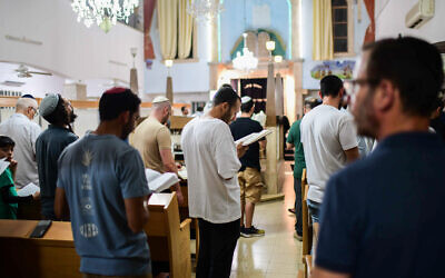 Jews gather on the eve of Tisha B'av at a synagogue in Tel Aviv for the annual reading of the Book of Lamentations, August 12, 2024. (Tomer Neuberg/Flash90)