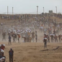 Displaced Palestinians carry food parcels and supplies from a Gaza Humanitarian Foundation aid distribution point along the Netzarim corridor in the central Gaza Strip, August 8, 2025. (Ali Hassan/Flash90)