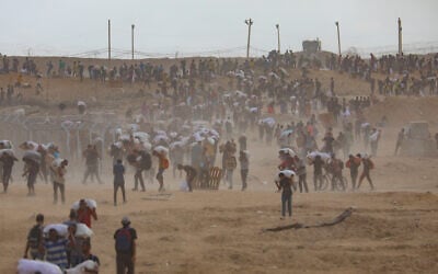 Displaced Palestinians carry food parcels and supplies from a Gaza Humanitarian Foundation aid distribution point along the Netzarim corridor in the central Gaza Strip, August 8, 2025. (Ali Hassan/Flash90)