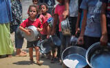 Palestinians receive meals from volunteers in Gaza City on August 10, 2025. (Ali Hassan/Flash90)