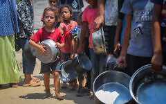 Palestinians receive meals from volunteers in Gaza City on August 10, 2025. (Ali Hassan/Flash90)