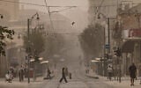 People walk across the light rail tracks on Jaffa Road in Jerusalem during a hazy summer day, August 11, 2025. (Chaim Goldberg/Flash90)