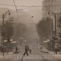 People walk across the light rail tracks on Jaffa Road in Jerusalem during a hazy summer day, August 11, 2025. (Chaim Goldberg/Flash90)