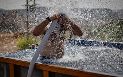 A Jewish man seeks relief from a heat wave in the central West Bank settlement of Beitar Illit, August 13, 2025. (Chaim Goldberg/Flash90)