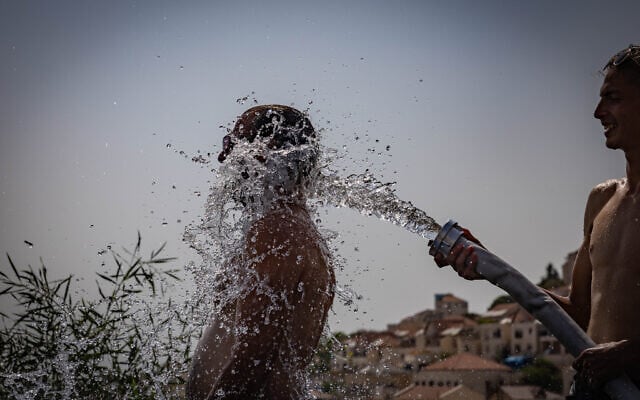 Men cool off with water in the West Bank settlement of Beitar Illit, amid a heat wave on August 13, 2025. Photo (Chaim Goldberg/Flash90) Men cool off with water in the West Bank settlement of Beitar Illit, amid a heat wave on August 13, 2025. Photo (Chaim Goldberg/Flash90)