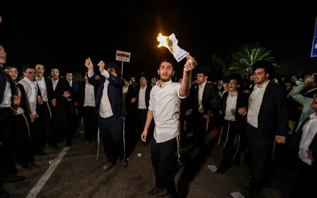 Ultra-Orthodox demonstrators burn enlistment orders at a demonstration outside the Beit Lid military prison, August 14, 2025. (Tal Gal/Flash90)
