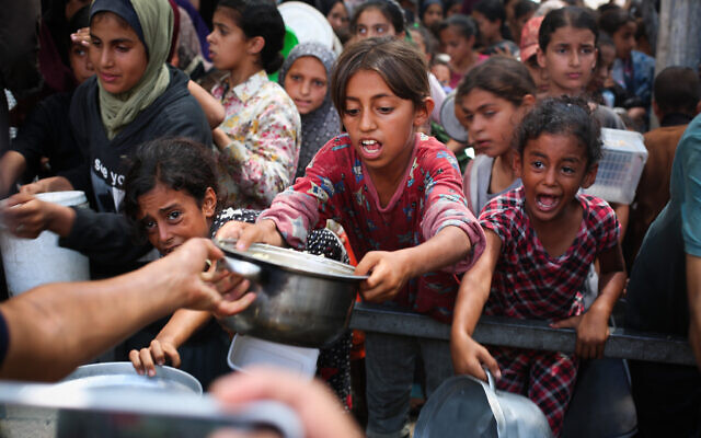 Palestinians receive meals from volunteers in Gaza City, on August 18, 2025. (Ali Hassan/Flash90)