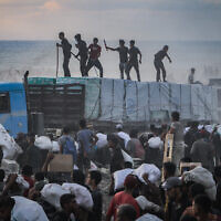 Armed Palestinians sit on trucks carrying humanitarian aid near the Zikim border crossing between Israel and Beit Lahia in the northern Gaza Strip on August 18, 2025. (Khalil Kahlout/ Flash90)