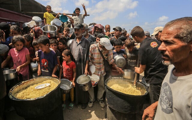 Palestinians receive a hot meal prepared by volunteers, in Khan Younis, in the southern Gaza Strip, August 21, 2025. (Abed Rahim Khatib/Flash90)