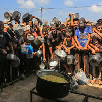 Palestinians wait to receive a hot meal prepared by volunteers, in Khan Younis, in the southern Gaza Strip, August 21, 2025. (Abed Rahim Khatib/Flash90)