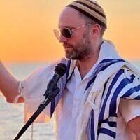At sunset by the water, Rabbi Ari Yehuda Saks leads a blessing with wine in hand and tallit draped over the shoulders (Courtesy / Moti Dolgin via JTA)
