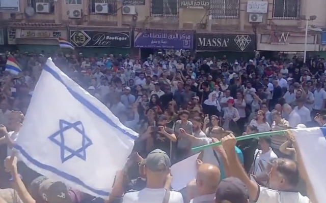 An Israeli flag is waved at a protest in Sweida in southern Syria on August 16, 2025. (Screenshot/X)