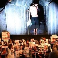 Protesters hold posters of the hostages in front of a still image taken from a Hamas video of hostage Evyatar David, on August 2, 2025. (Paulina Patimer/ Hostages and Missing Families Forum)