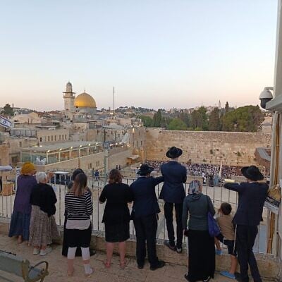 Visitors look out at the Western Wall on Tisha B'Av, August 3, 2025 (Zev Stub/Times of Israel)