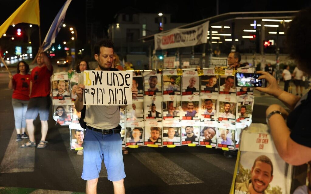 A protester holds a sign reading "We have forgotten what it means to be Jewish" in front of posters of the Gaza hostages, at a protest in Tel Aviv on August 30, 2025. (Yoav Loeff/Pro-Democracy Protest Movement)