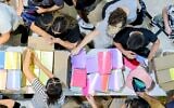 Volunteers for Latet fill backpacks with basic educational supplies for the new school year. (Yakir Amos)