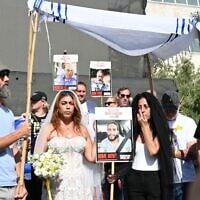 Ilana Gritzewsky (center), John Polin (left), and Einav Zangauker (right) stage a mock wedding between Gritzewsky and her boyfriend Matan Zangauker who is still being held captive in Gaza, on August 17, 2025, in Hostages Square in Tel Aviv (Paulina Patimer / Hostages and Missing Families Forum)