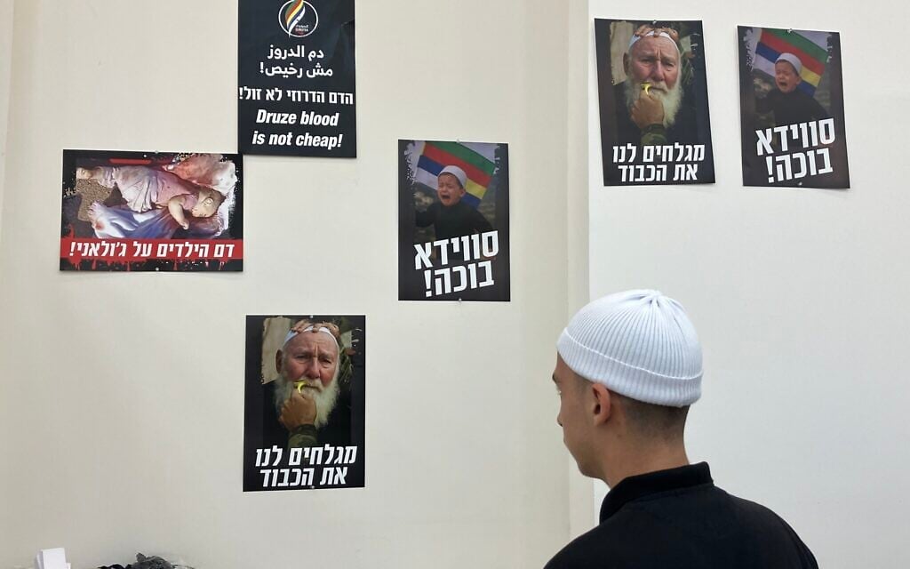 A Druze volunteer looks at s photograph of a Syrian Druze cleric, Marhej Shahine, whose mustache was forcibly shaved by armed men in Sweida, Syria in the war room in Julis on August 6, 2025. (Diana Bletter/Times of Israel)