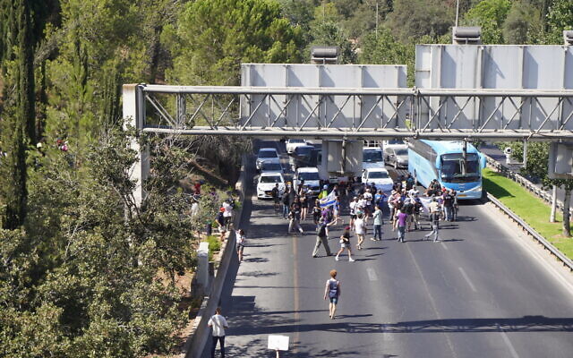Protesters demanding a hostage and ceasefire deal begin to gather on Begin Highway in Jerusalem, blocking the road to traffic on August 17, 2025. (Charlie Summers/ Times of Israel)