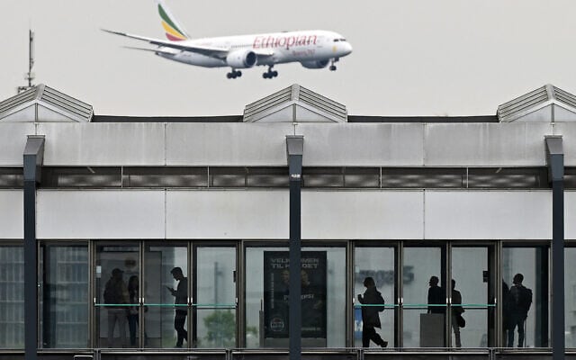 People wait for a train at a metro station as an Ethiopian Airlines Boeing 787-8 passenger plane flies in the sky during landing at the Copenhagen Airport in Copenhagen, Denmark, on June 4, 2025. (Photo by Sergei GAPON / AFP)